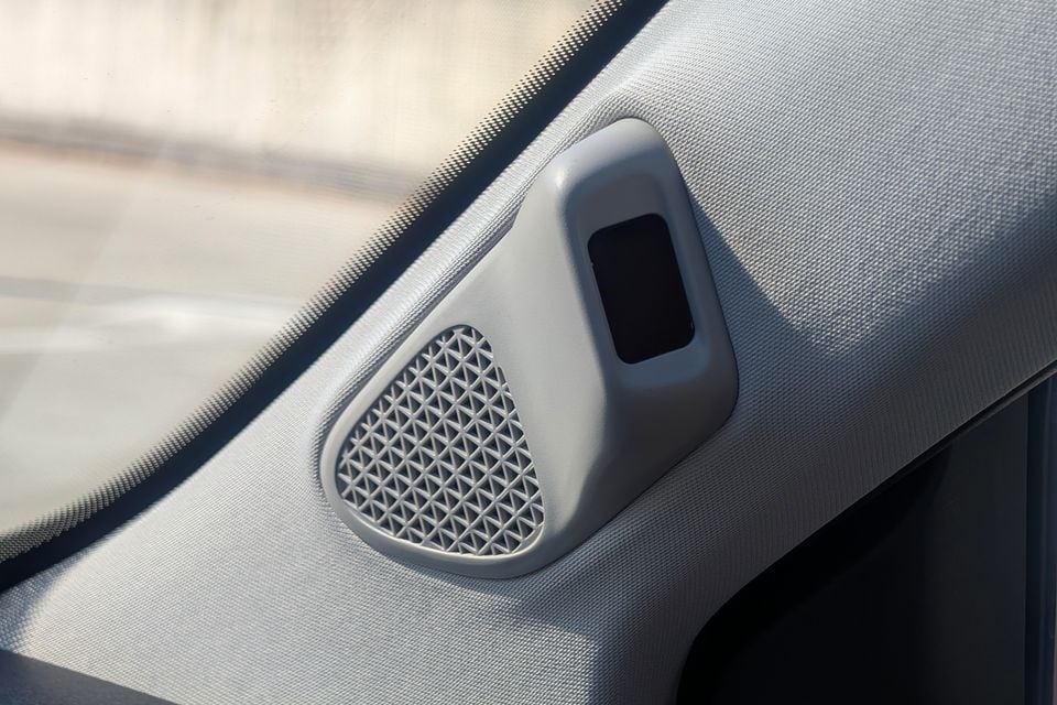 Close-up of a door-mounted tweeter speaker grille and window switch panel on the interior door trim of a GAC Aion V