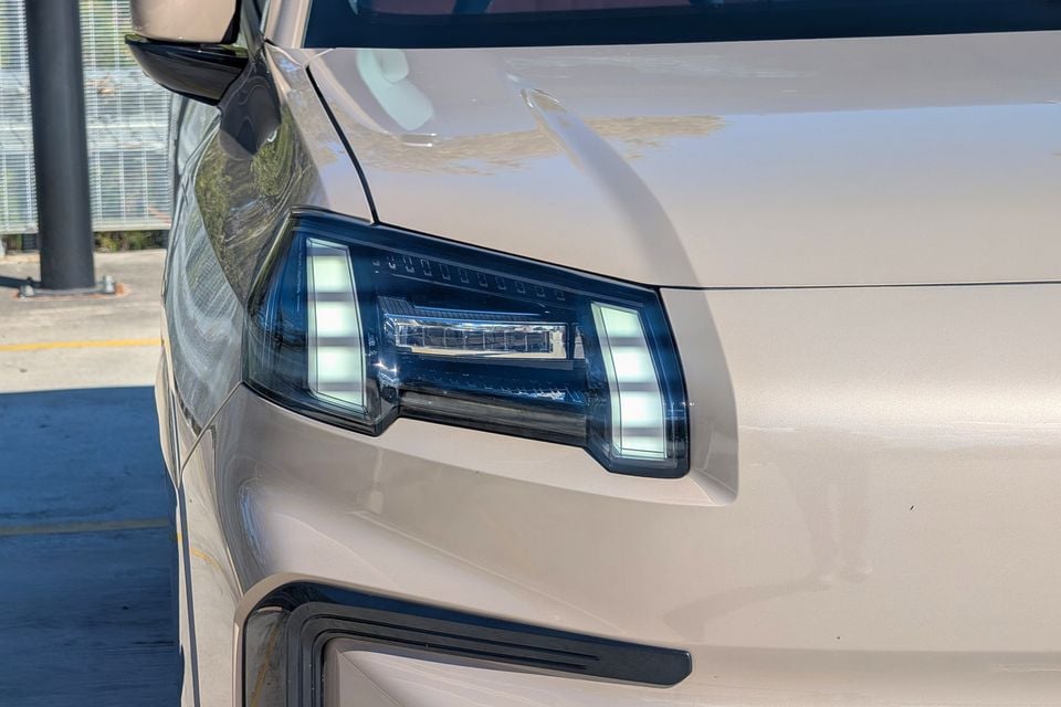 Close-up of the LED headlight on a beige GAC Aion V, seen from the front corner