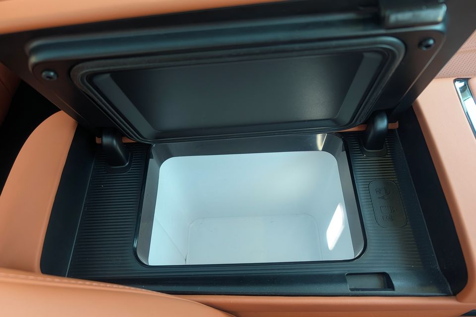 Open centre console storage compartment with a white removable tray, surrounded by tan leather interior trim