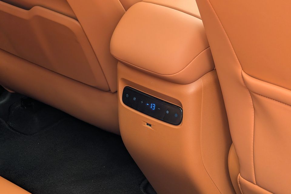 Rear passenger seat climate control panel with heating and cooling buttons on tan leather upholstery in a GAC Aion V, with a USB port below