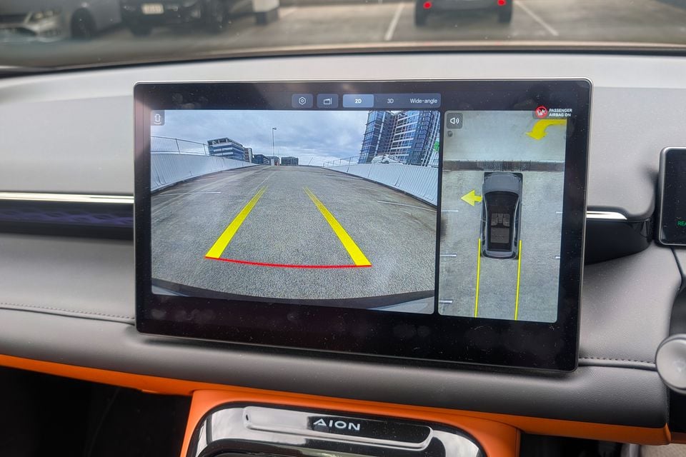 The touchscreen infotainment display in a GAC Aion V showing the reversing camera feed with parking guidelines and a bird's-eye surround-view display