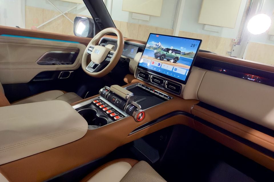 Interior of the 2027 Geely Battleship 700 showing the dashboard, large central touchscreen, tan and cream leather upholstery, and off-road-style centre console with red-lit controls