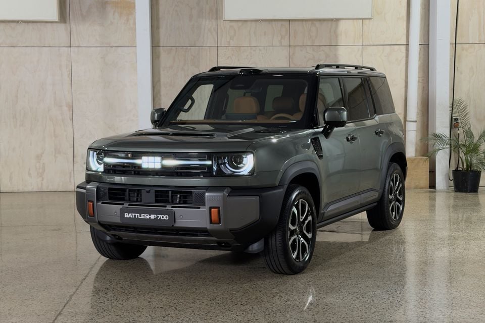 A dark green Geely Battleship 700 SUV photographed from the front-side angle inside a showroom