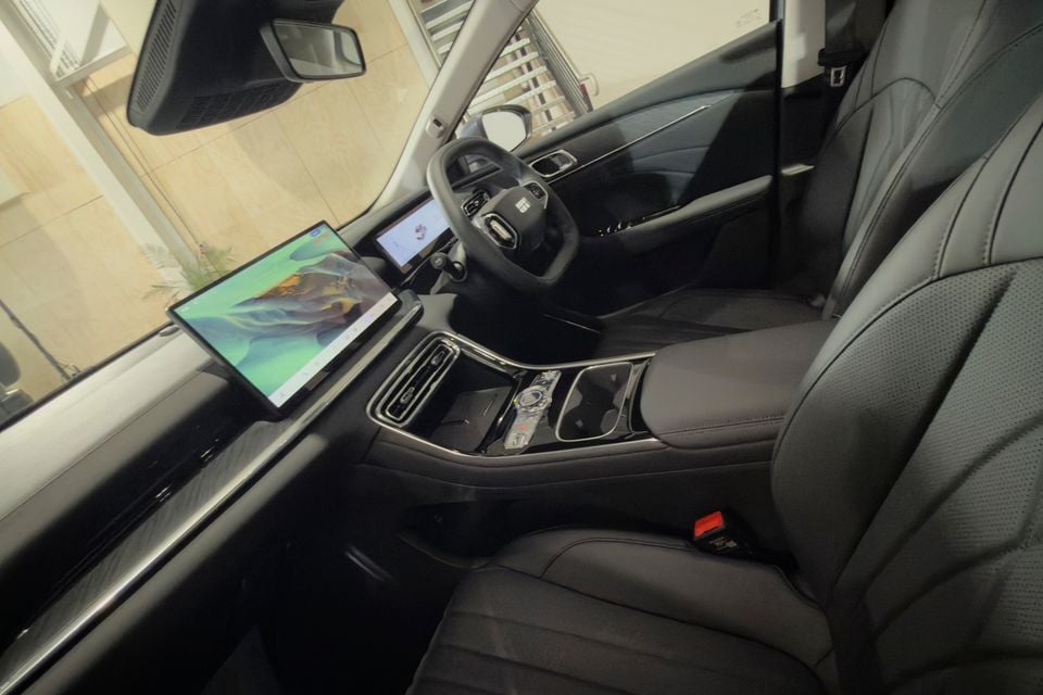 Interior of a Geely Emgrand L showing the dashboard, large central touchscreen, steering wheel, centre console and dark leather front seats