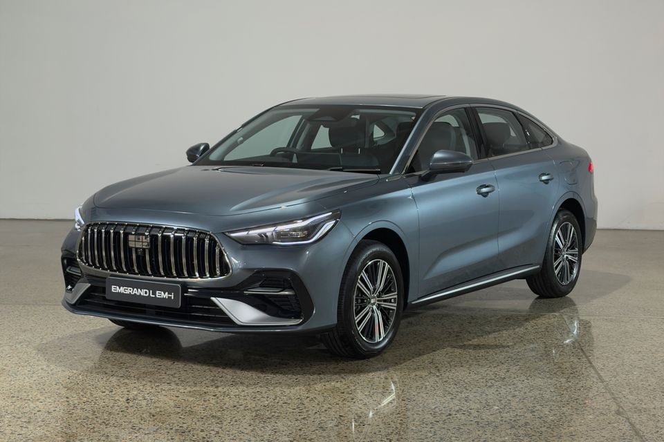 A grey Geely Emgrand L EM-i sedan seen from the front three-quarter angle in a studio setting