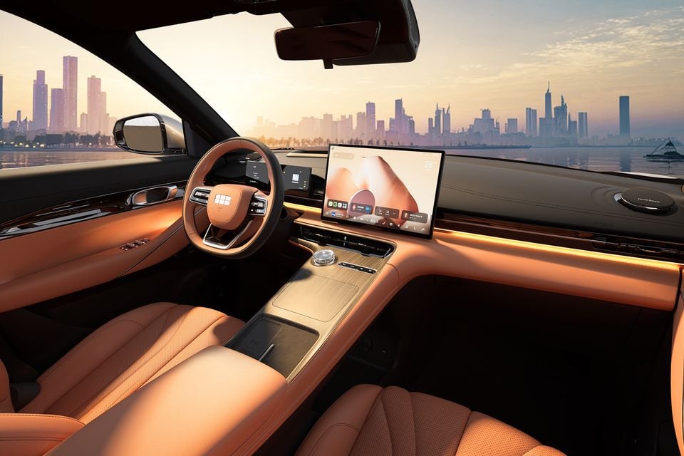 The tan leather interior of a Geely Galaxy E5 shows the steering wheel, dashboard and infotainment screen with a city skyline visible through the windscreen.