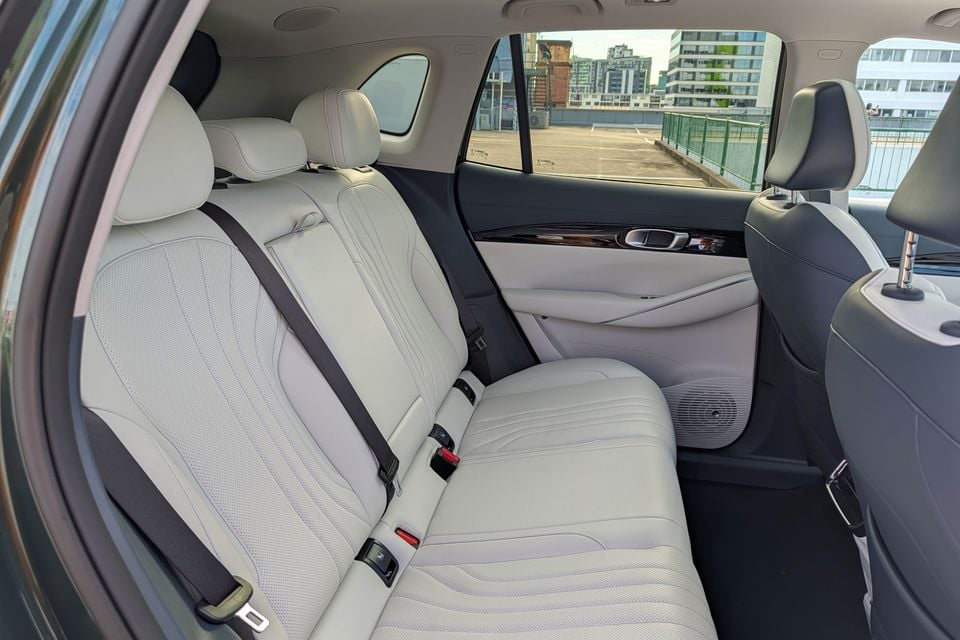 Rear seat interior of a Geely GX5 showing light cream leather upholstery with three seatbelts and a wood-trim door panel