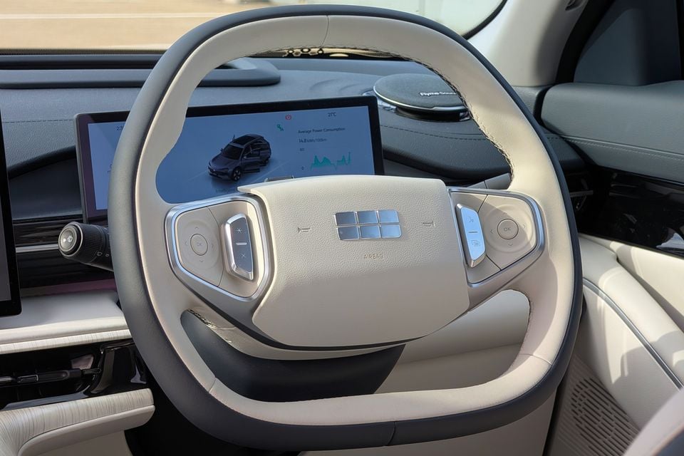Close-up of the Geely GX5 Inspire steering wheel showing control buttons and the touchscreen infotainment display in the background