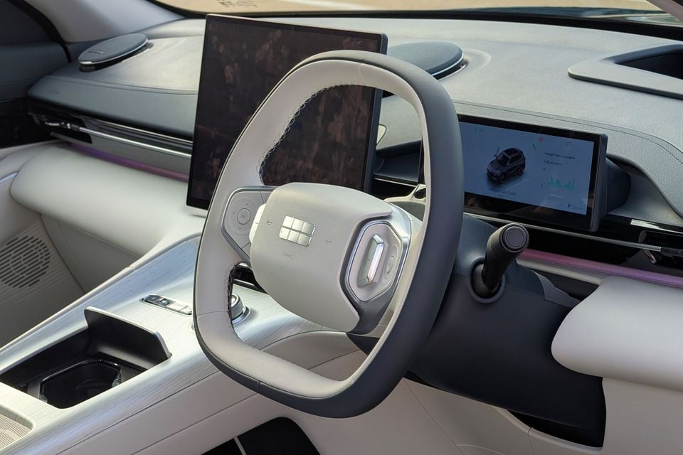Interior view of the 2027 Geely GX5 Inspire showing the steering wheel, large central touchscreen, and instrument cluster display with a light-coloured cabin