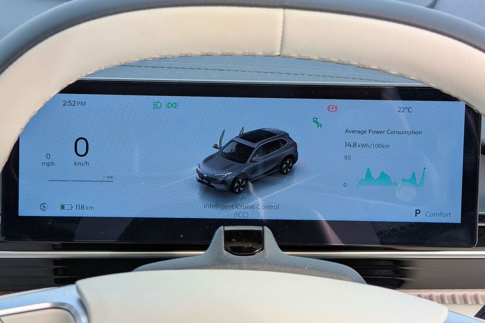 The digital instrument cluster of a Geely GX5 showing speed, battery range of 118km, average power consumption of 14.8kWh/100km, and Intelligent Cruise Control status on a wide display screen framed by a two-tone steering wheel.