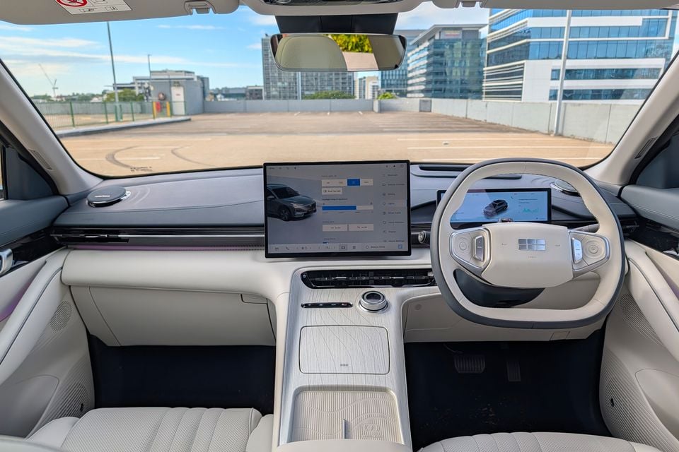 Interior of the Geely GX5 showing the large central touchscreen infotainment display, digital instrument cluster, steering wheel, and light-coloured dashboard and console