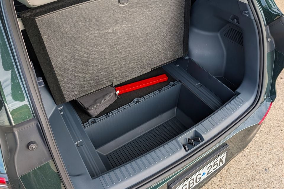 Boot of a green Geely GX5 Inspire with the floor panel lifted to reveal an under-floor storage compartment containing a warning triangle and tool bag