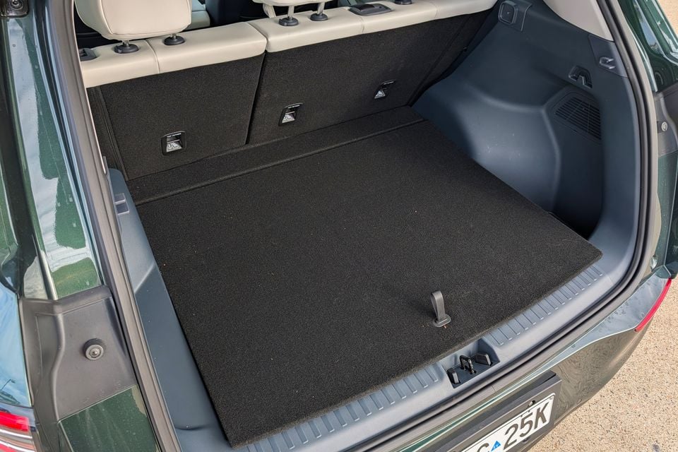 The open boot of a green Geely GX5 SUV, showing a flat carpeted load floor with top-tether anchor points and rear seat backrests visible