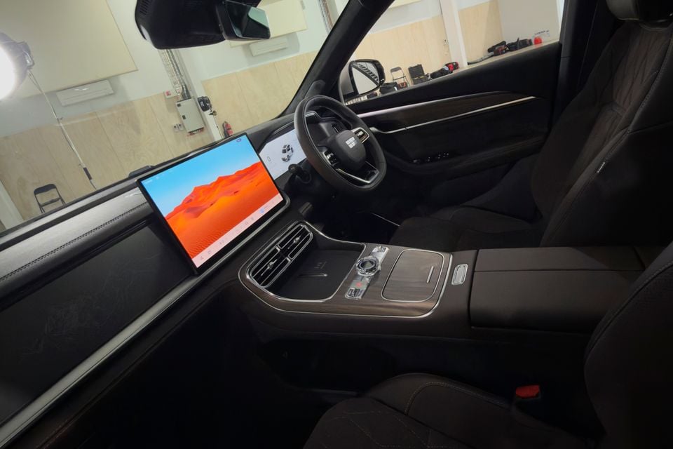 Interior of a Geely Monjaro showing a large landscape-oriented touchscreen infotainment display, centre console, and steering wheel with dark upholstery