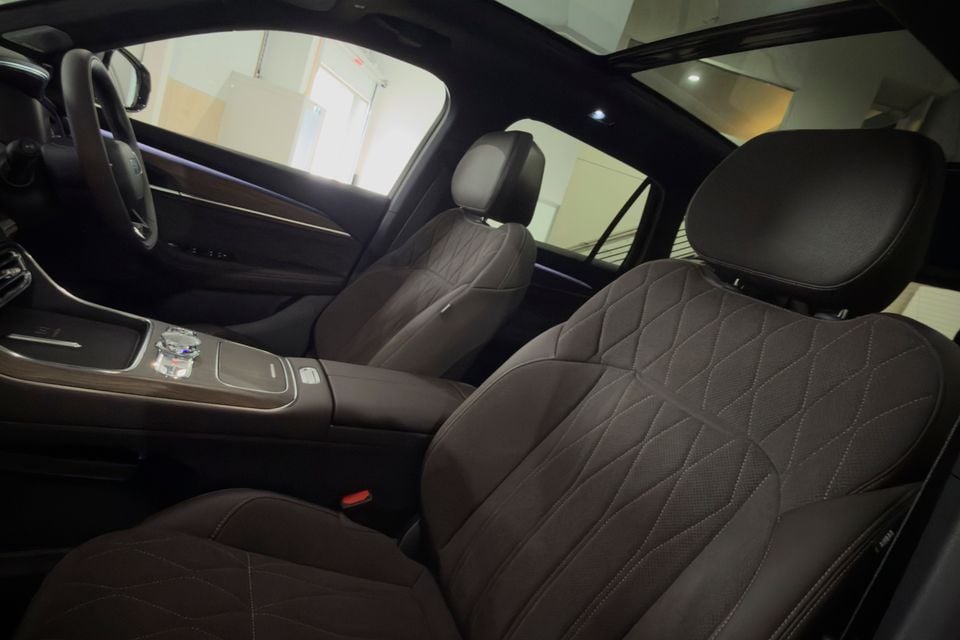 Interior view of a Geely Monjaro showing quilted dark leather front seats, centre console, and panoramic sunroof
