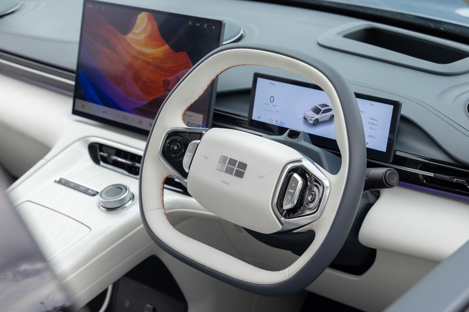 Steering wheel, digital instrument display and central touchscreen in the white and grey cabin of the 2027 Geely Starray EM-i Inspire