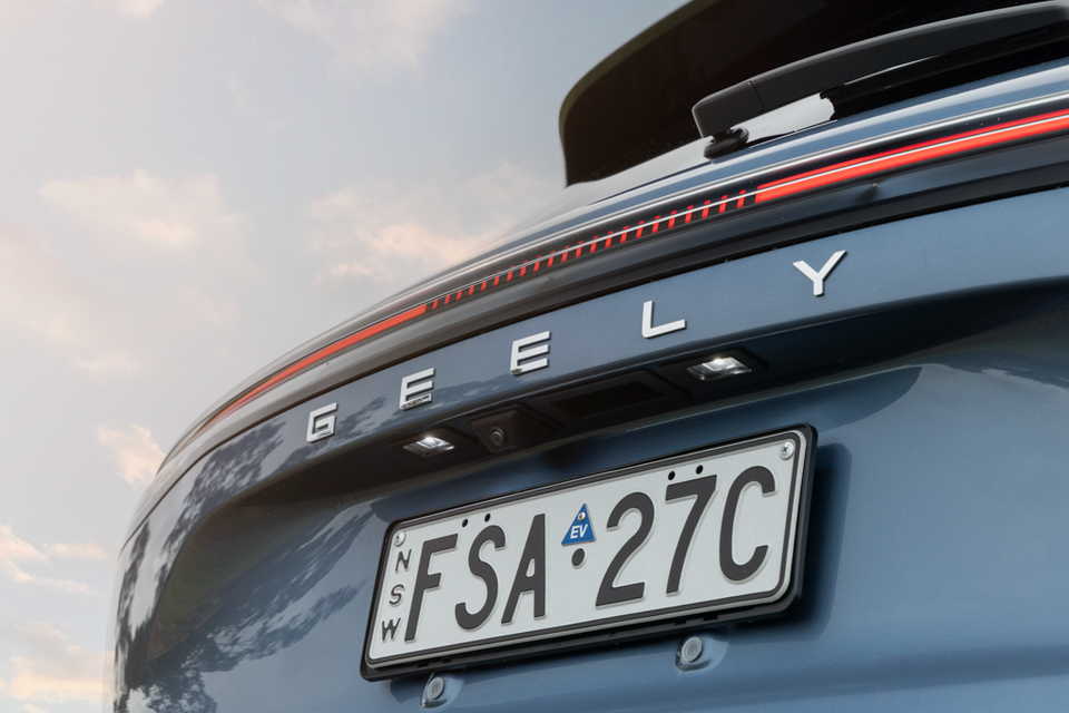 Close-up of the rear of a blue Geely Starray EM-i showing the Geely lettering, full-width red light bar and NSW EV number plate