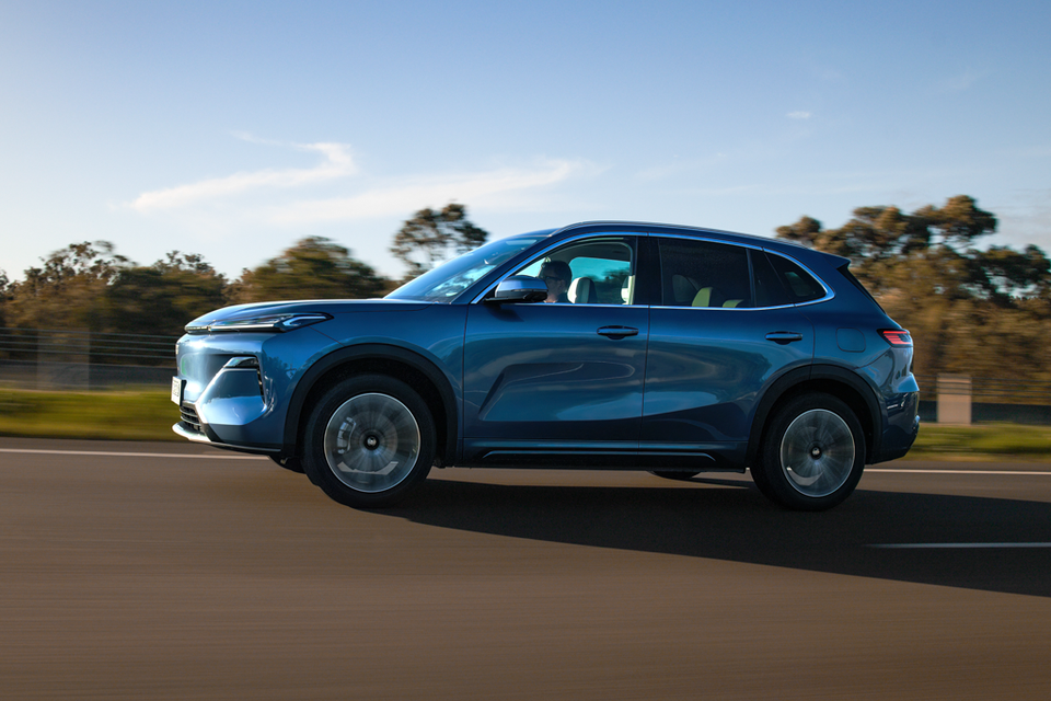 A blue 2027 Geely Starray EM-i SUV driving along a road, seen from the side