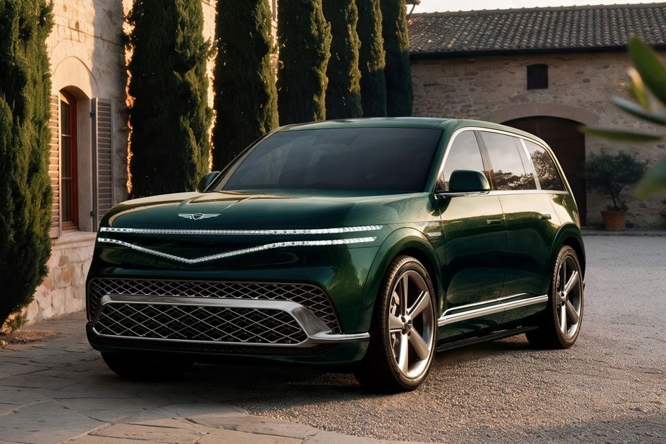 A dark green 2027 Genesis GV90 large SUV seen from the front-side angle, parked outside a stone villa with cypress trees in the background.