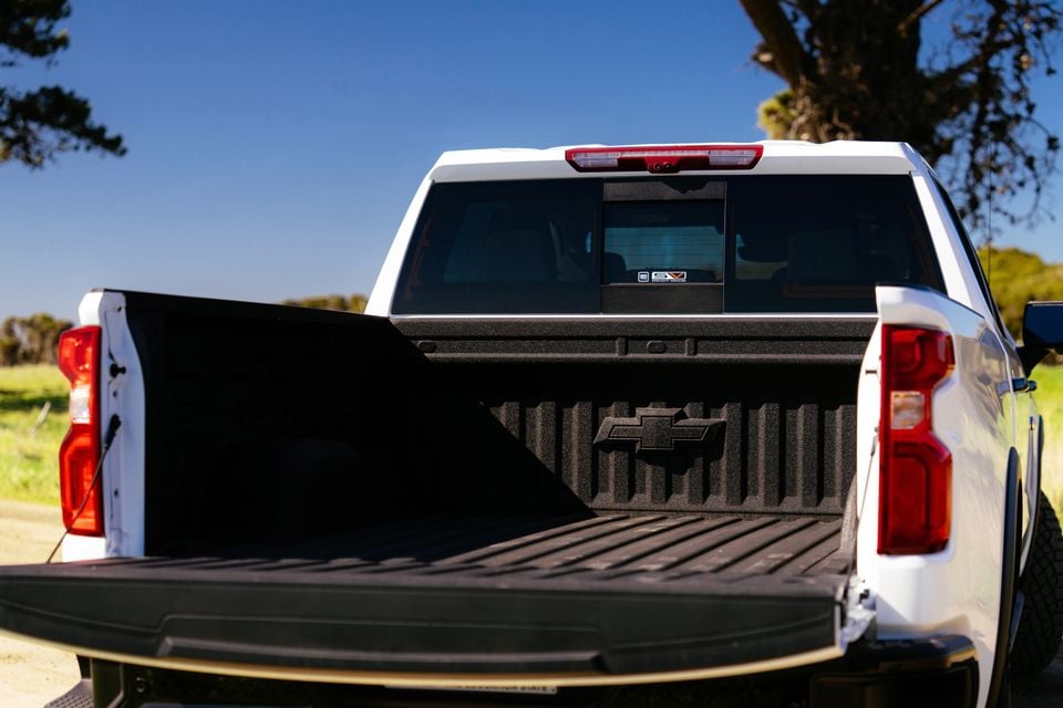 The open tray bed of a white Chevrolet Silverado ute, showing the spray-lined tub and Chevrolet bowtie badge, seen from the rear outdoors