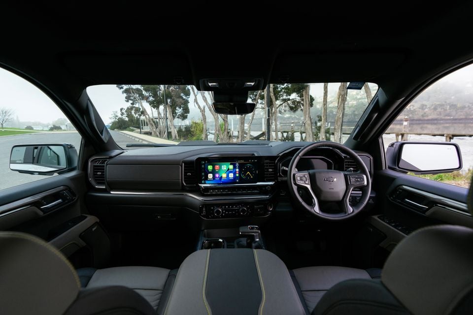Interior view of a Chevrolet Silverado ZR2 showing the dashboard, large touchscreen infotainment display with Apple CarPlay, Chevrolet-badged steering wheel, and two-tone grey and black seats with yellow stitching