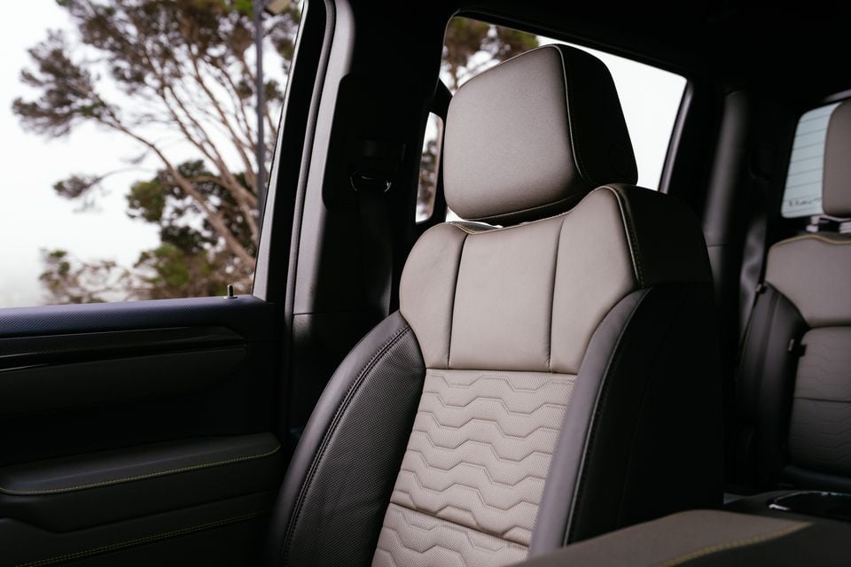 Two-tone beige and black leather front seat interior of the 2027 Chevrolet Silverado ZR2, showing geometric stitching detail and yellow accent stitching on the door trim.