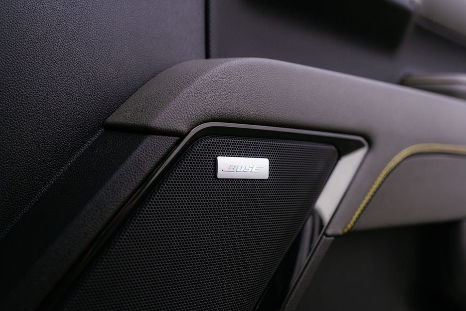 A Bose speaker on the door panel of a 2027 GMSV Chevrolet Silverado ZR2, with dark trim and contrast yellow stitching visible nearby.
