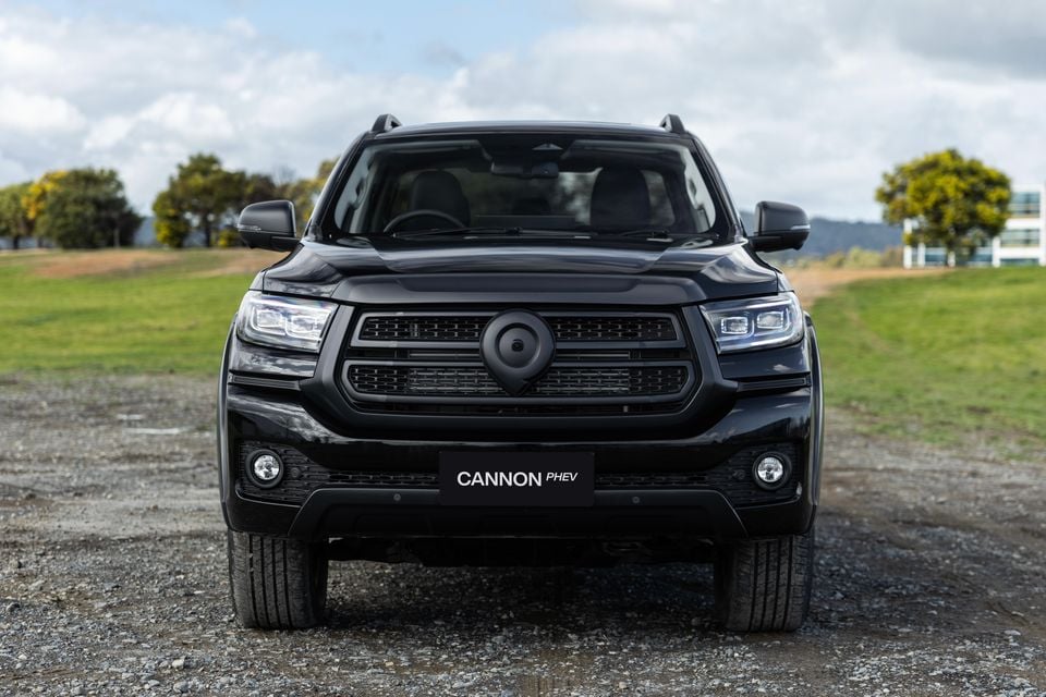 Front view of a black GWM Cannon PHEV ute parked on gravel, showing its bold grille and LED headlights.