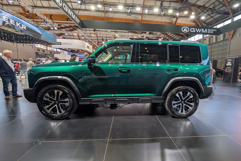 A green GWM Haval H7 large SUV displayed at a motor show, seen from the side