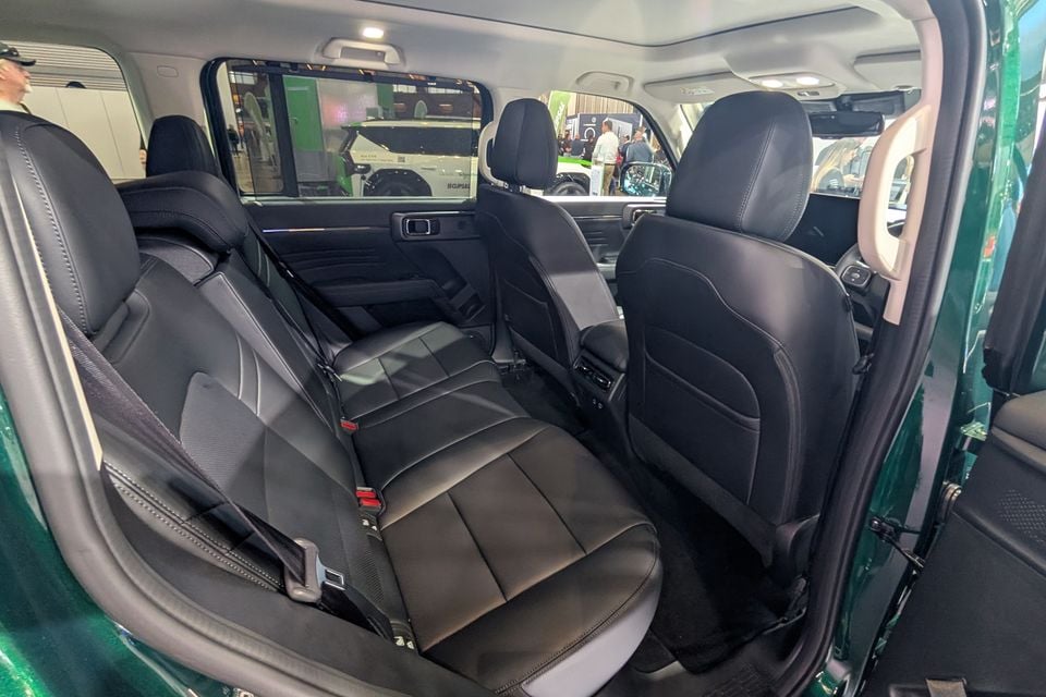 Rear passenger seats of a GWM Haval H7 with black leather upholstery, viewed from an open door at a motor show