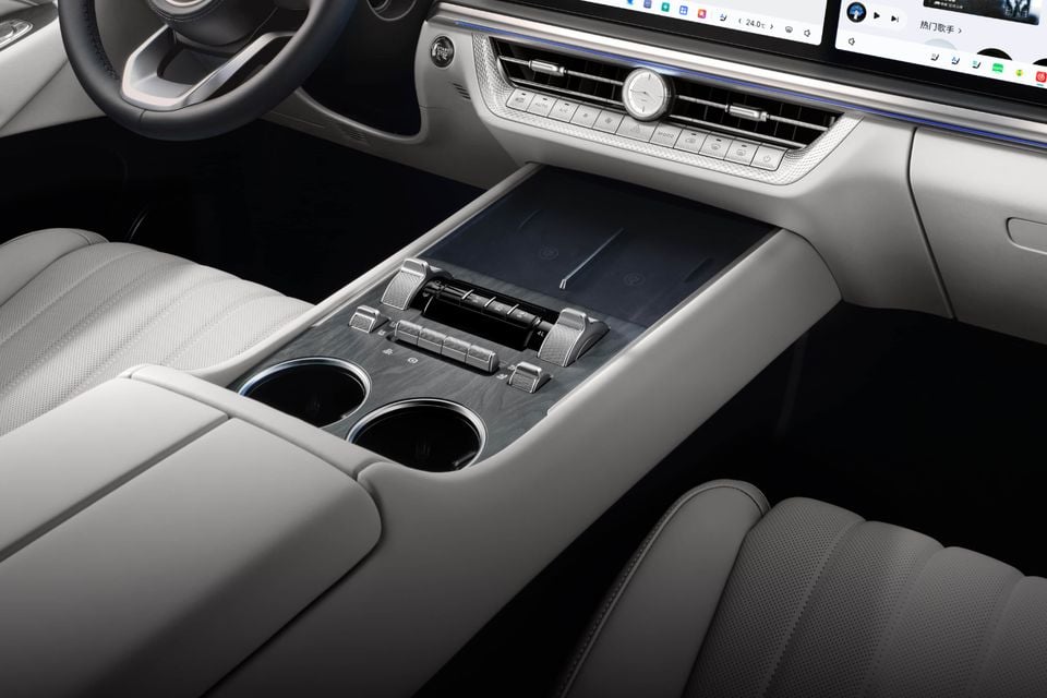 Centre console of the 2027 GWM Tank 500 with light grey leather seats, cupholders, wireless charging pads and climate controls below the screens