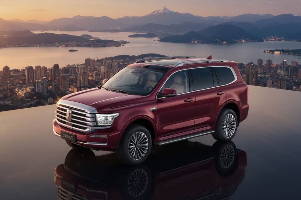 A dark red 2027 GWM Tank 500 SUV parked on a reflective rooftop overlooking a city, bay and mountains at sunset