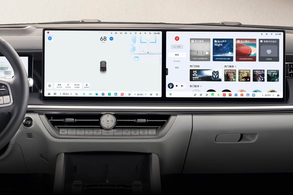 Dashboard of the 2027 GWM Tank 500 with dual touchscreens showing a driving display and music app, an analogue clock and climate controls below