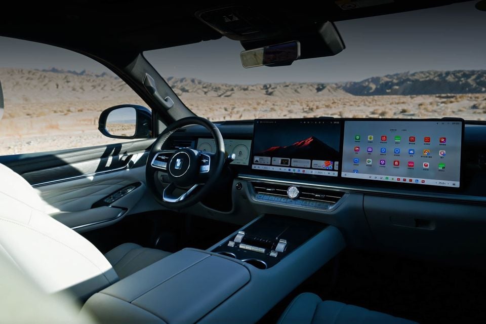 Dashboard of the 2027 GWM Tank 500 with steering wheel, dual widescreen displays and cream leather seats, overlooking a desert landscape