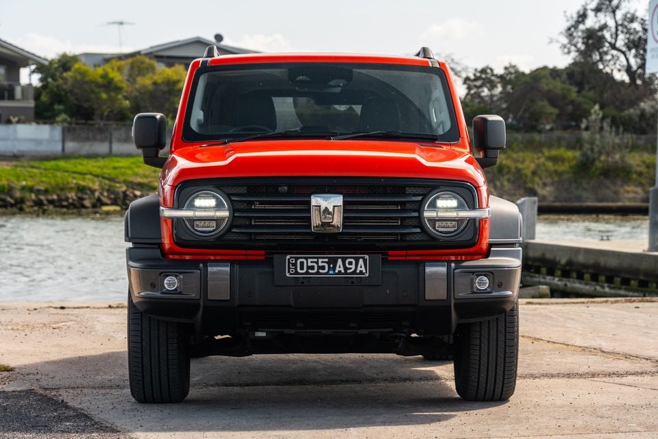 A red GWM Tank 300 Ultra PHEV 4WD SUV seen from the front, parked near a waterway in Australia