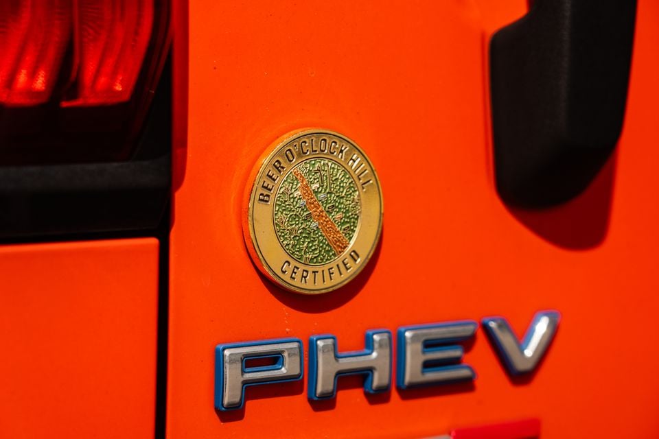 A gold 'Beer O'Clock Hill Certified' badge and PHEV emblem on the orange exterior of a GWM Tank 300 PHEV