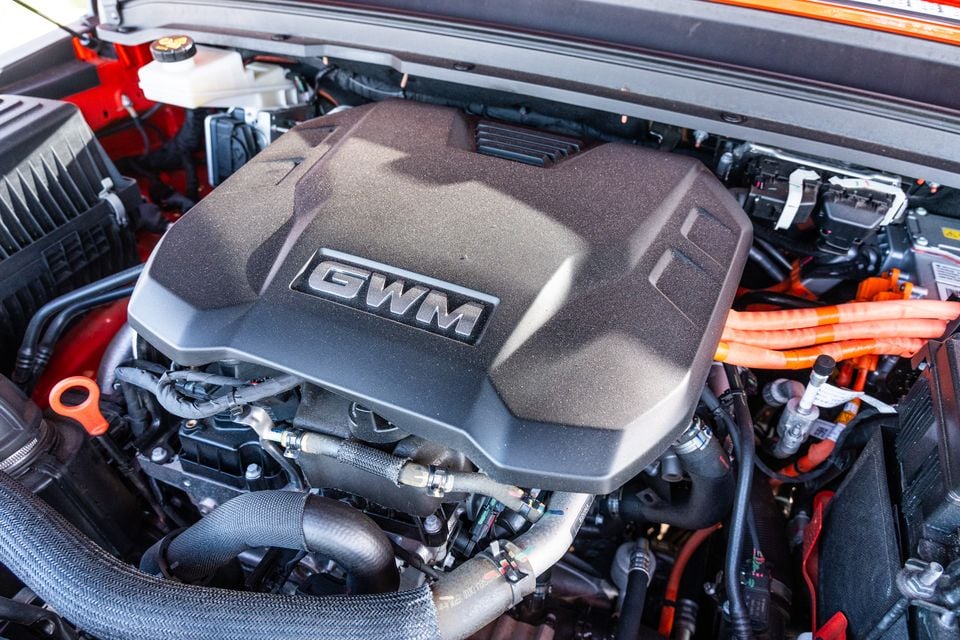 GWM engine bay showing the GWM-branded engine cover with orange high-voltage cables, indicating a plug-in hybrid powertrain