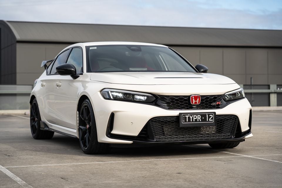A white Honda Civic Type R hatchback seen from the front three-quarter angle in a car park