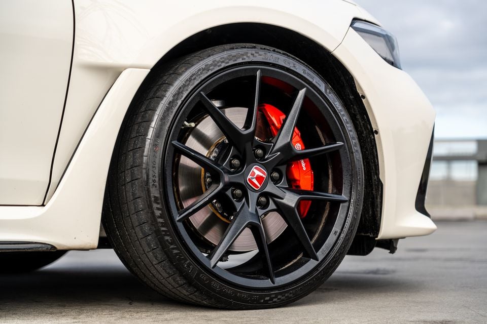 Close-up of a black multi-spoke alloy wheel with red Brembo brake calipers and a Honda Type R centre cap on a white Honda Civic Type R