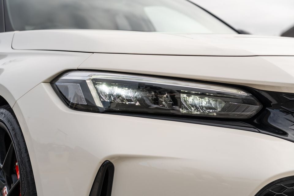 Close-up of the LED headlight on a white Honda Civic Type R, showing the front corner and wheel arch detail.
