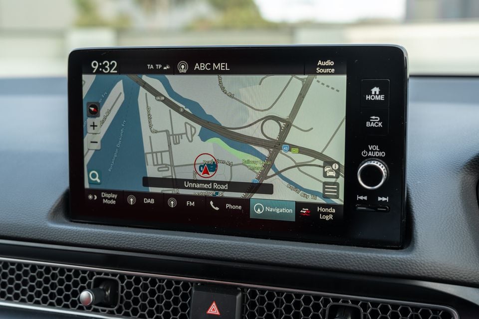 The infotainment touchscreen of a Honda Civic Type R showing the built-in navigation map near Melbourne's Docklands, with DAB radio tuned to ABC Melbourne and physical controls to the right.