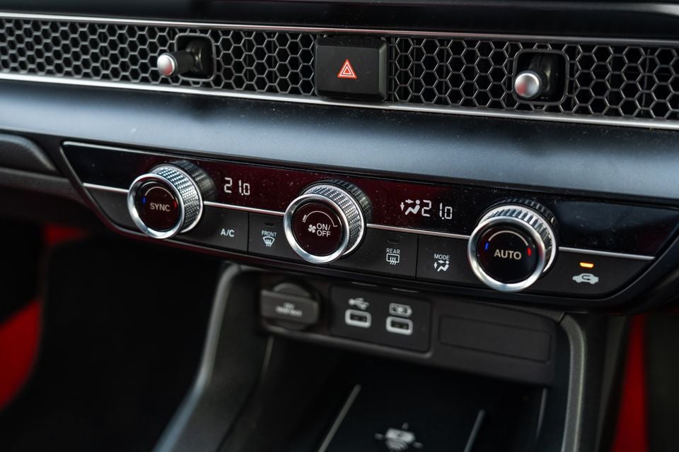 Close-up of the dual-zone climate control panel inside a Honda Civic Type R, showing temperature dials set to 21 degrees, fan speed, A/C, and mode buttons with USB ports below