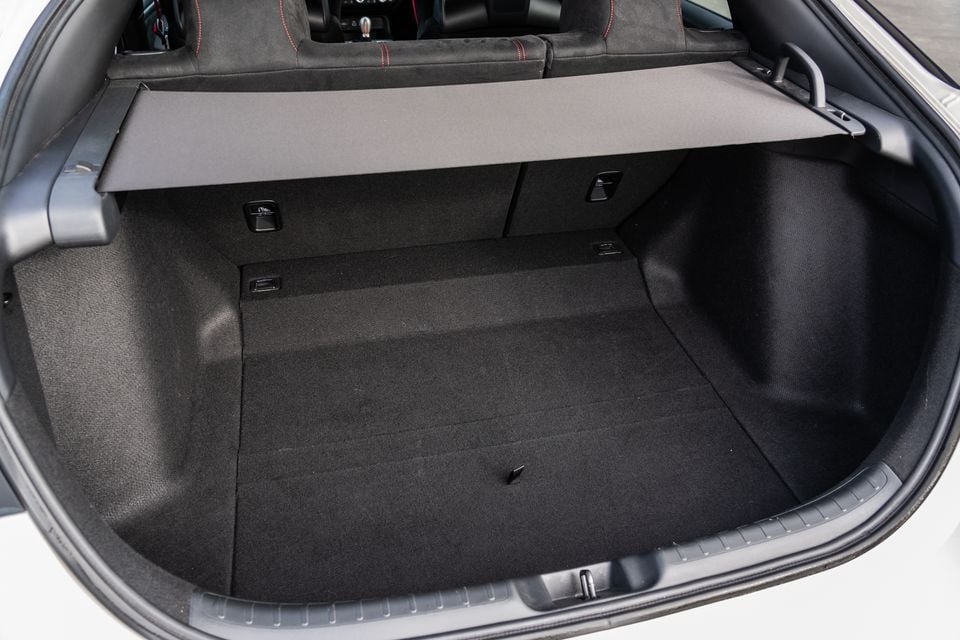 Boot space of a Honda Civic Type R with the cargo cover in place, showing a carpeted load floor and split-folding rear seat backs