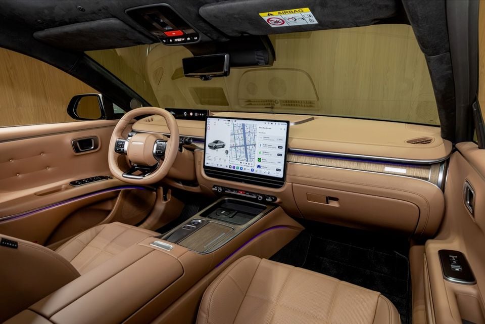 Interior of the 2027 Hyundai Grandeur Pleos showing tan leather seats, a large central touchscreen displaying a navigation map, and a wood-trimmed dashboard with ambient purple lighting.