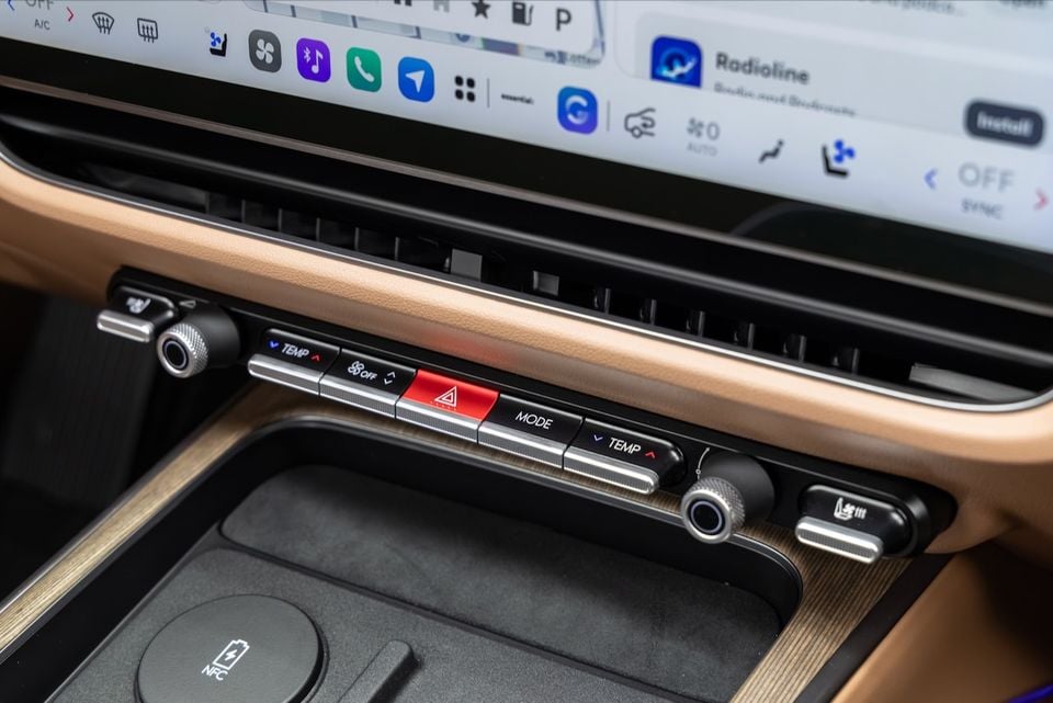 Interior of a Hyundai Grandeur showing the climate control panel with temperature and mode buttons, hazard light switch, dual dials, and a large touchscreen infotainment display above