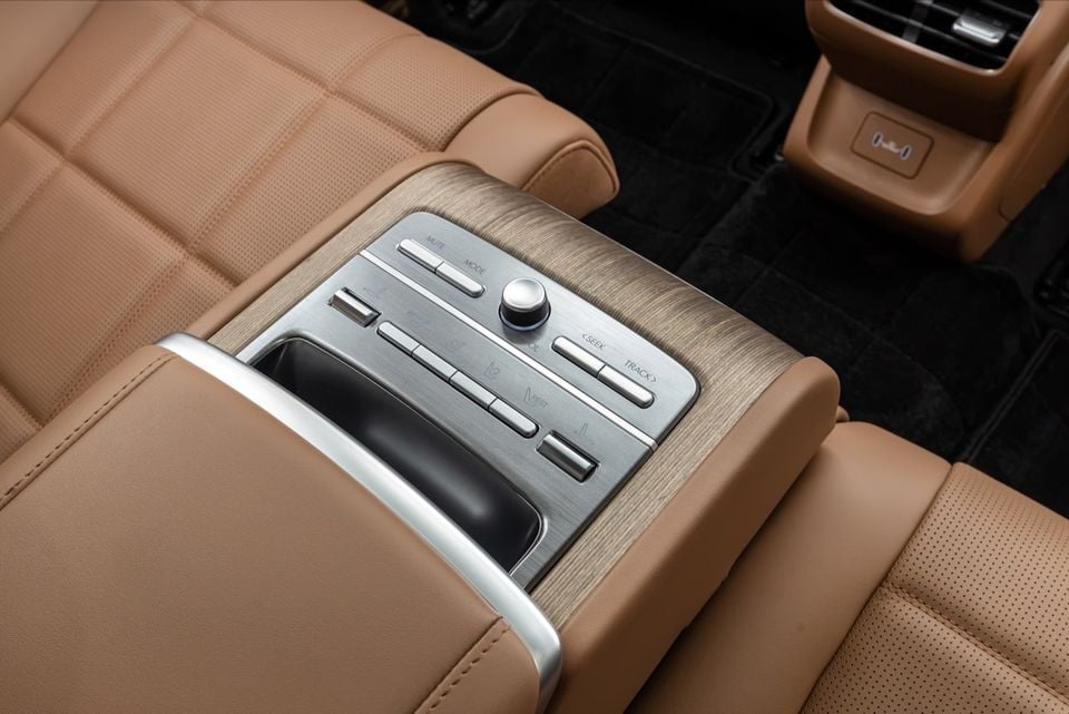 Rear centre console controls panel with audio and climate buttons set in wood trim, flanked by tan leather seats inside the 2027 Hyundai Grandeur Pleo