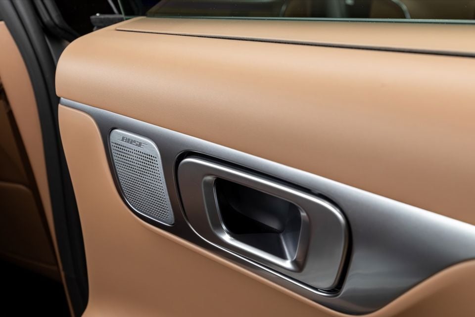 Close-up of a tan leather car door panel showing a Bose speaker grille and interior door handle