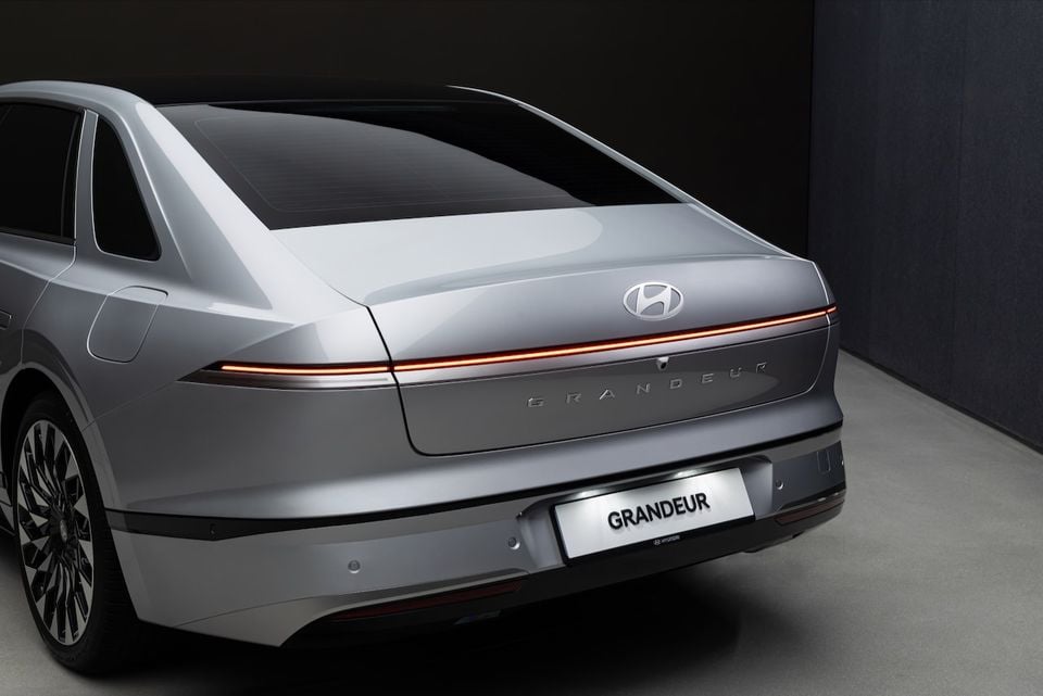 Rear view of a silver Hyundai Grandeur sedan, showing the full-width light bar, Hyundai badge, and Grandeur lettering across the boot lid.