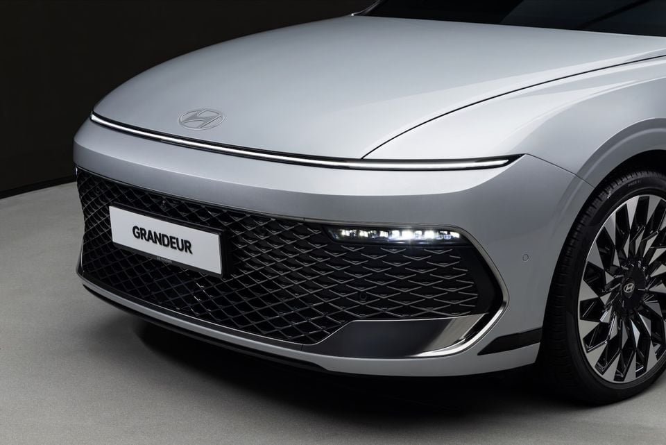 Close-up of the front end of a silver Hyundai Grandeur, showing the large mesh grille, LED daytime running lights, and Hyundai badge on the bonnet.