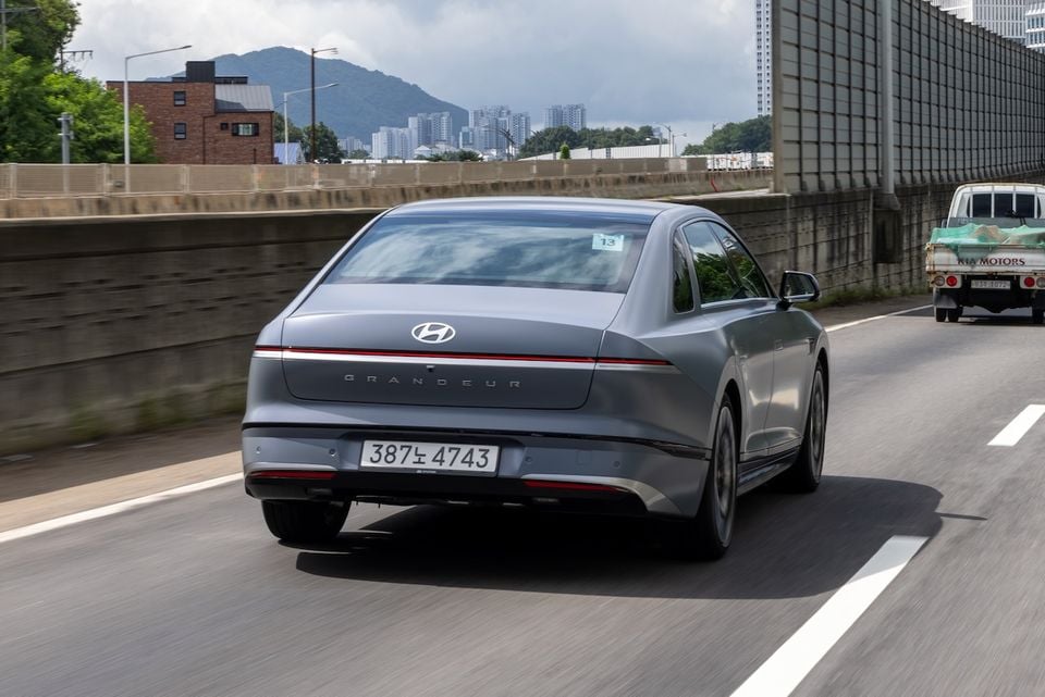 A grey Hyundai Grandeur sedan seen from the rear while driving on a highway